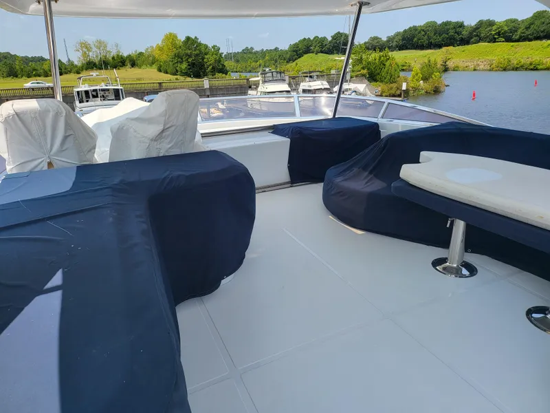Slide: The Image of Spacious deck of 2000 Horizon 74 Motor Yacht with covered seating, docked by a scenic river. - 8