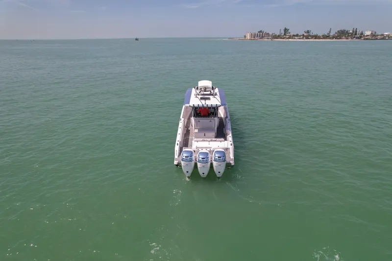 Slide: The Image of 2020 Nor-Tech 390 Sport Center Console cruising on calm waters near coastal homes. - 8