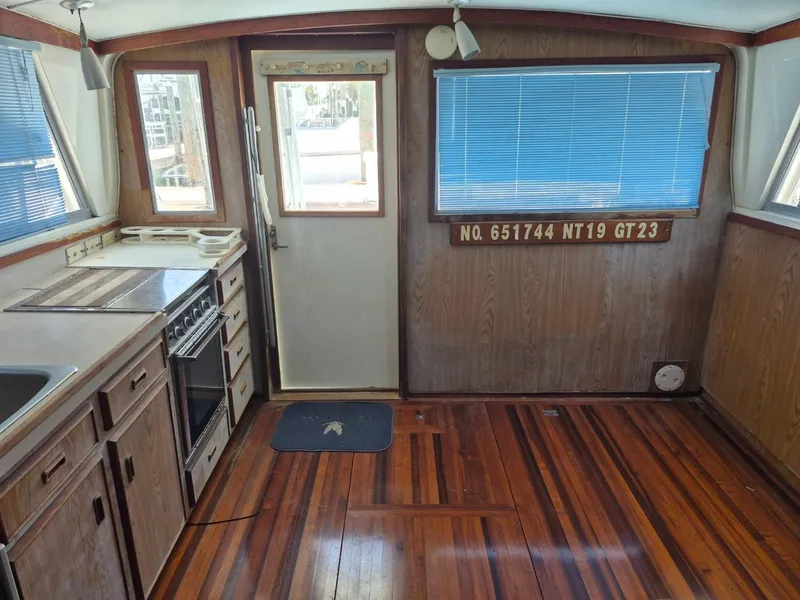 Slide: The Image of Interior of a 1982 Bertram 38 Convertible boat with wood flooring and kitchen area. - 13