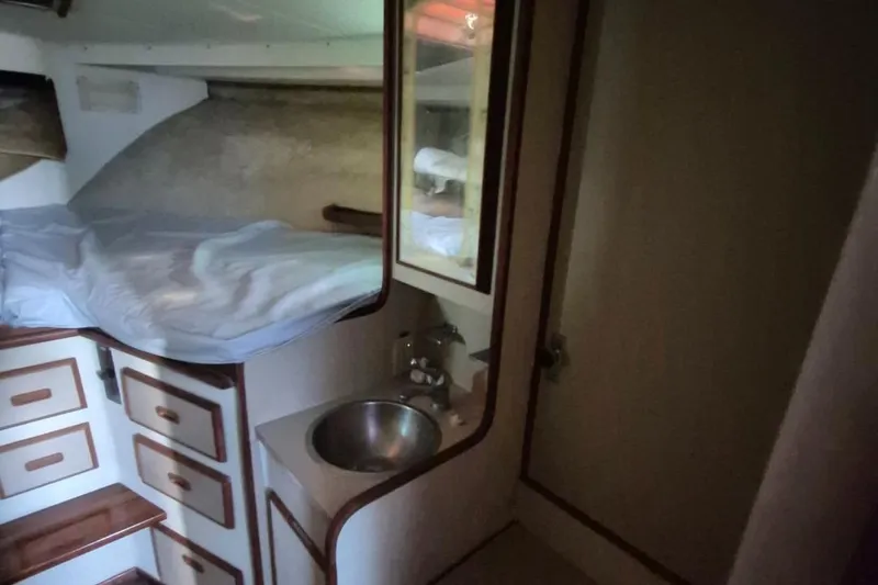 Slide: The Image of 1982 Bertram 38 Convertible cabin interior with bed, sink, and storage drawers. - 24