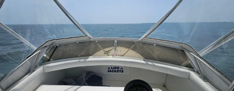 Slide: The Image of 1982 Bertram 38 Convertible boat on open sea, clear sky, life jackets visible. - 47