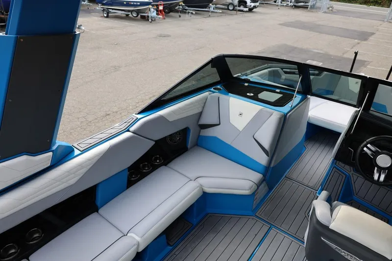 Slide: The Image of 2022 Nautique Super Air Nautique S23 interior with blue and gray seating, cup holders, and speaker. - 16