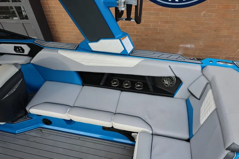 Slide: The Image of 2022 Nautique Super Air Nautique S23 interior with blue and white seating and cup holders. - 17