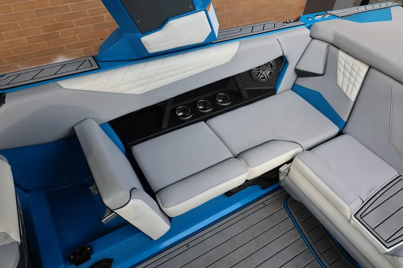 Slide: The Image of 2022 Nautique Super Air Nautique S23 interior with blue and white seating, cup holders, and speaker. - 25