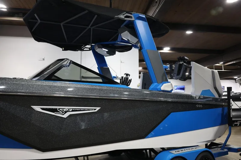 Slide: The Image of 2022 Nautique Super Air Nautique S23 boat in showroom, featuring sleek design and blue accents. - 52