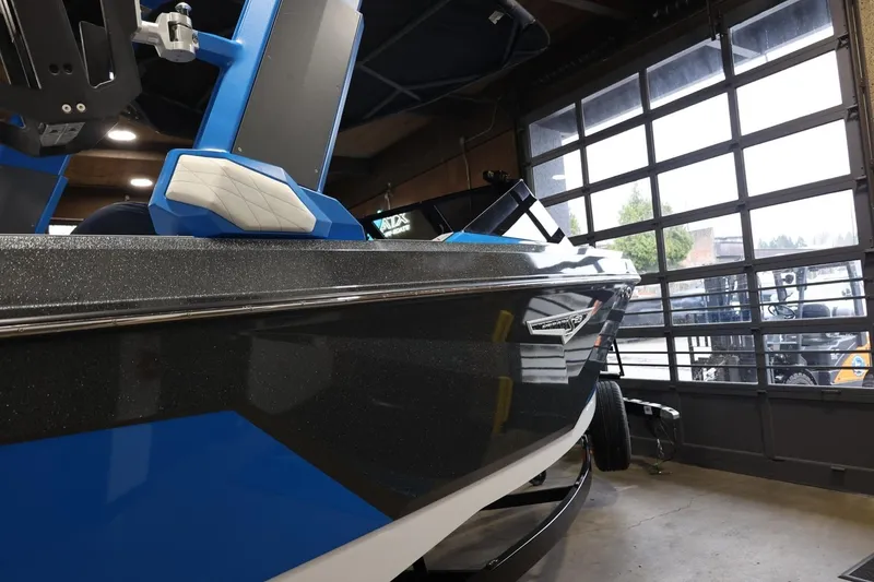 Slide: The Image of 2022 Nautique Super Air Nautique S23 boat in showroom, blue and black design. - 58