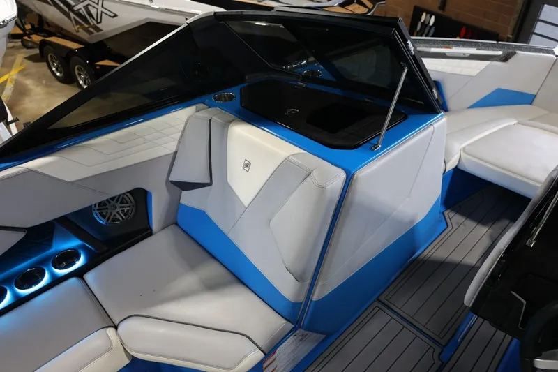 Slide: The Image of 2022 Nautique Super Air Nautique S23 interior with blue and white seating, cup holders, and speaker. - 72