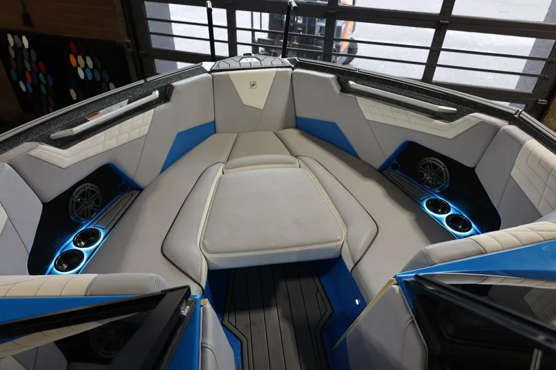 Slide: The Image of 2022 Nautique Super Air Nautique S23 boat interior with blue accents and cup holders. - 73