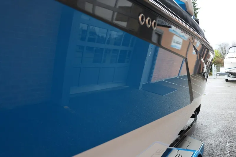Slide: The Image of 2022 Nautique Super Air Nautique S23 boat with sleek blue hull in a parking area. - 86