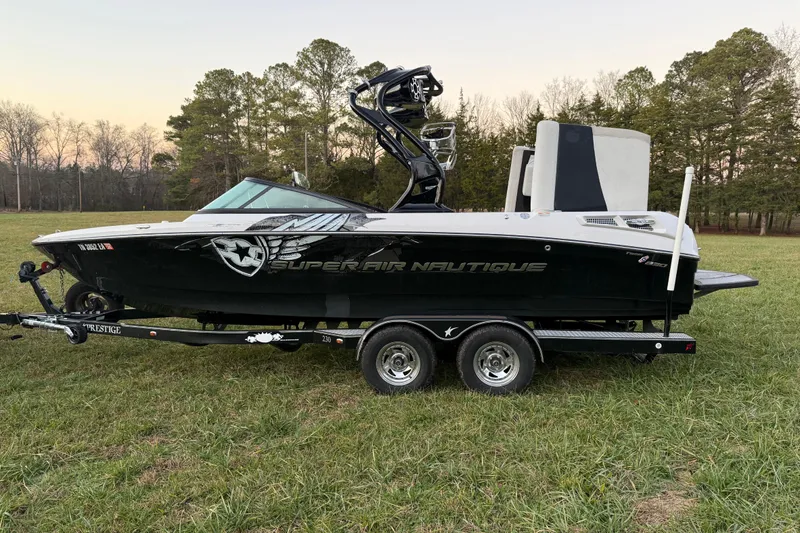 Slide: The Image of 2010 Nautique Super Air Nautique 230 boat on trailer in grassy field. - 3