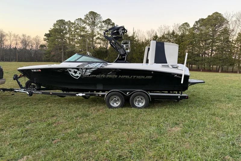 Slide: The Image of 2010 Nautique Super Air Nautique 230 boat on trailer in grassy field. - 4
