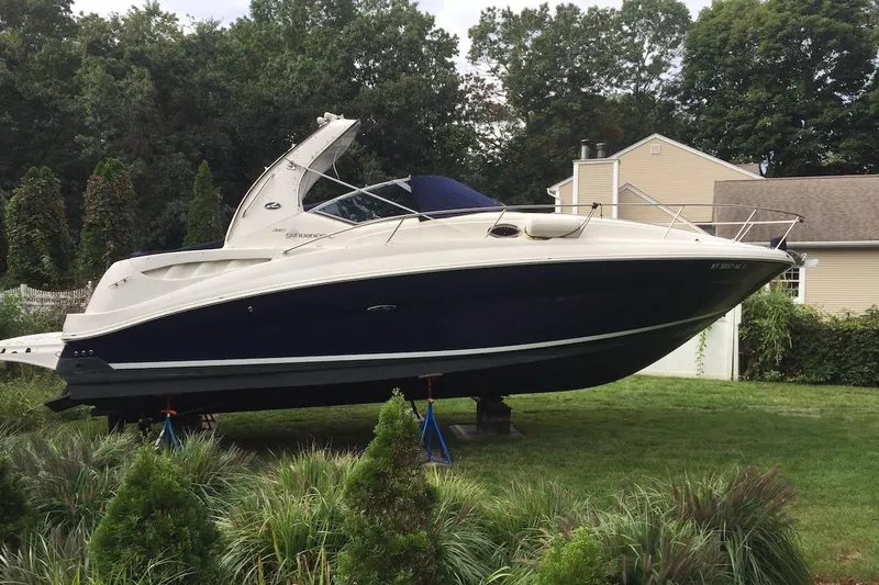 Slide: The Image of 2004 Sea Ray 320 Sundancer boat on land, surrounded by greenery and a house. - 3
