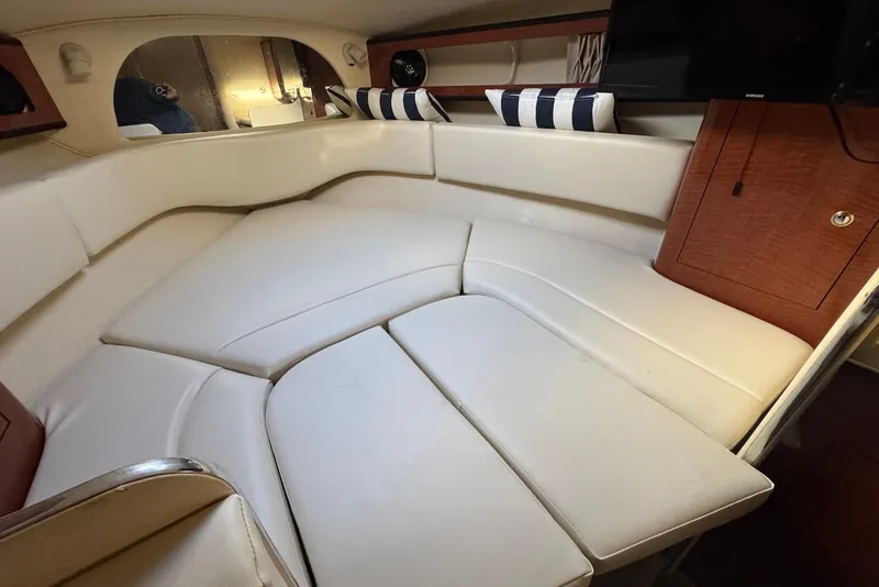 Slide: The Image of 2004 Sea Ray 280 Sundancer cabin interior with white seating and striped pillows. - 11