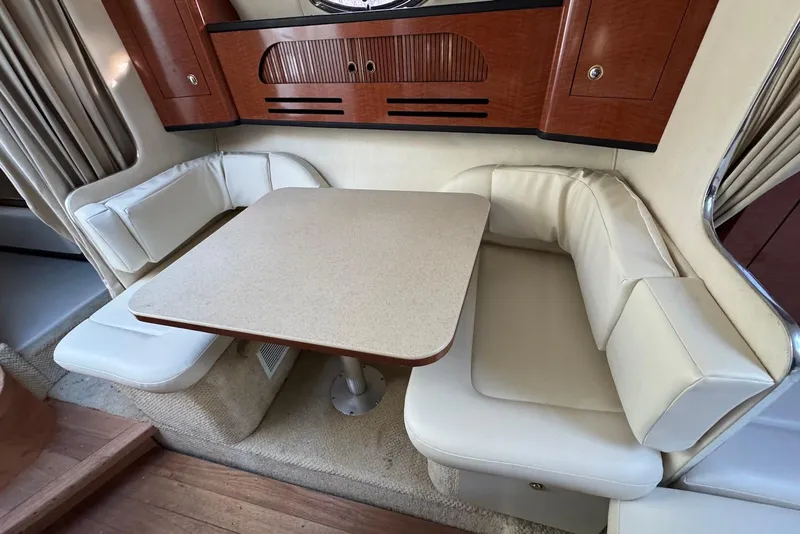 Slide: The Image of 2004 Sea Ray 280 Sundancer interior with beige seating and wooden cabinetry. - 12