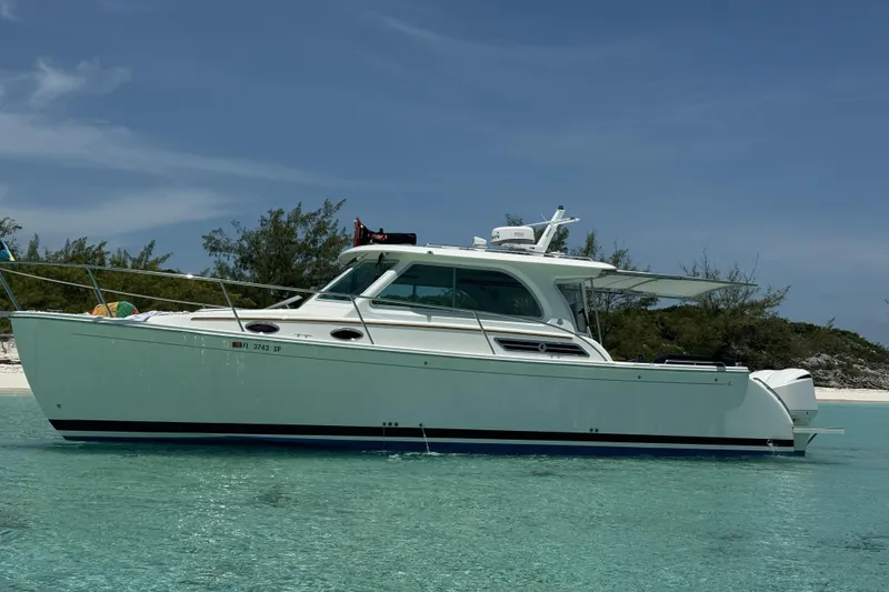 The Image of 2020 Back Cove 34O boat anchored in clear turquoise water near a sandy beach. - 0