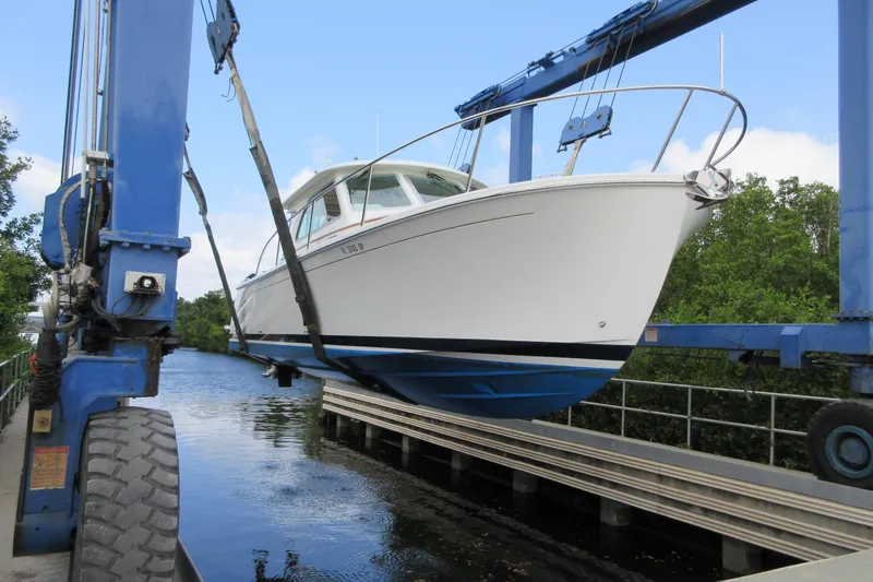 Slide: The Image of 2020 Back Cove 34O boat being lifted by a crane over water. - 14