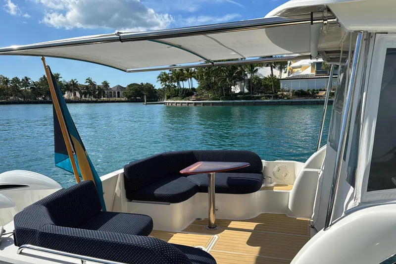 Slide: The Image of 2020 Back Cove 34O boat with seating area, table, and scenic waterfront view. - 2