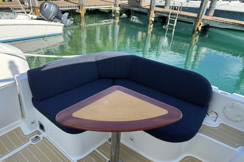 Slide: The Image of Cozy seating area on 2020 Back Cove 34O boat with triangular table, docked by clear water. - 21