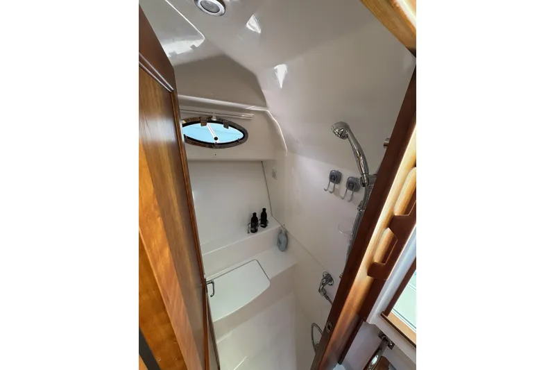 Slide: The Image of 2020 Back Cove 34O yacht bathroom with shower, wooden accents, and porthole window. - 38