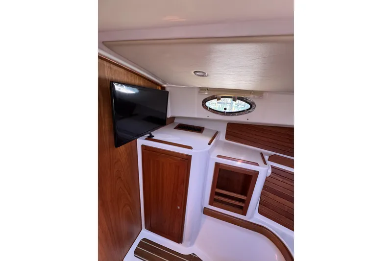 Slide: The Image of 2020 Back Cove 34O cabin interior with TV, wood accents, and porthole window. - 41