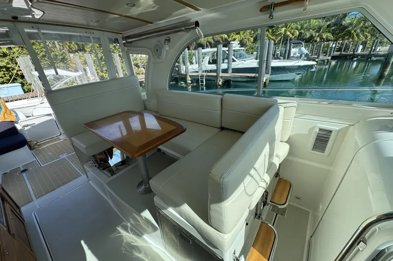 Slide: The Image of 2020 Back Cove 34O interior with white seating, wooden table, and marina view. - 7