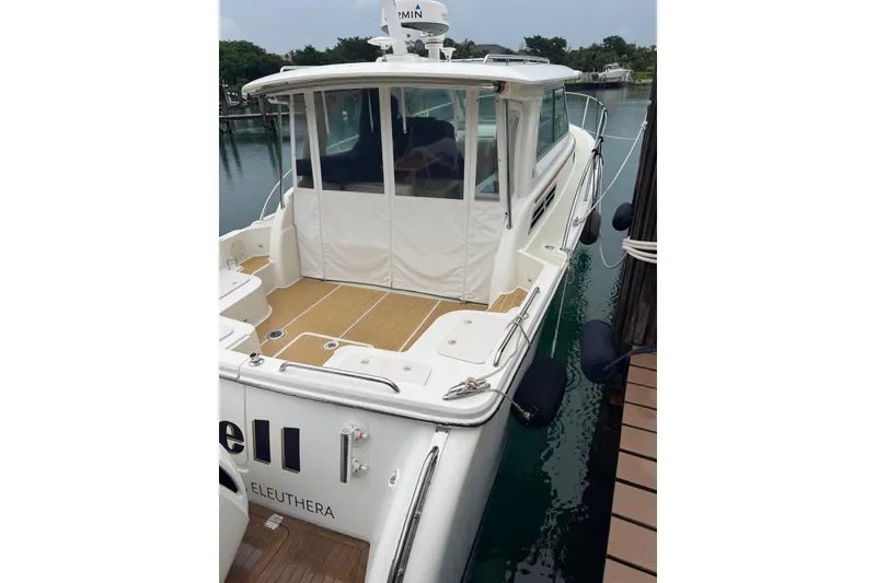 Slide: The Image of 2020 Back Cove 34O boat docked, featuring a spacious deck and enclosed cabin. - 8