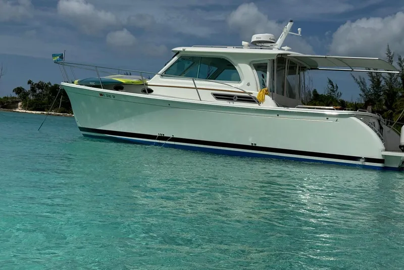Slide: The Image of 2020 Back Cove 34O boat anchored in clear turquoise water, under a partly cloudy sky. - 9