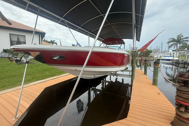 Slide: The Image of 2007 Cobalt 343 boat in red, docked under a canopy by a waterfront home. - 1