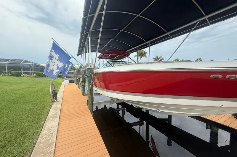 Slide: The Image of Red 2007 Cobalt 343 boat docked under canopy with flag, near green lawn. - 4