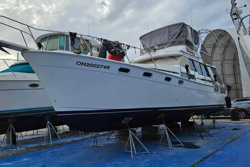 Slide: The Image of 1991 Bayliner 3888 Motoryacht docked, featuring tan canvas covers and visible name "Shoreline Traveller." - 2