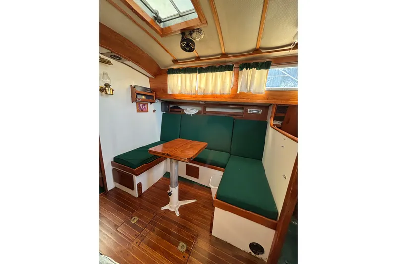 Slide: The Image of Interior of a 1968 Spencer 35 sailboat with green seating and wooden table. - 18