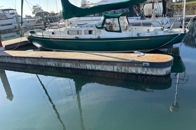 Slide: The Image of Sailboat docked at marina, Spencer 35 model, 1968, with green canopy and calm water reflection. - 2