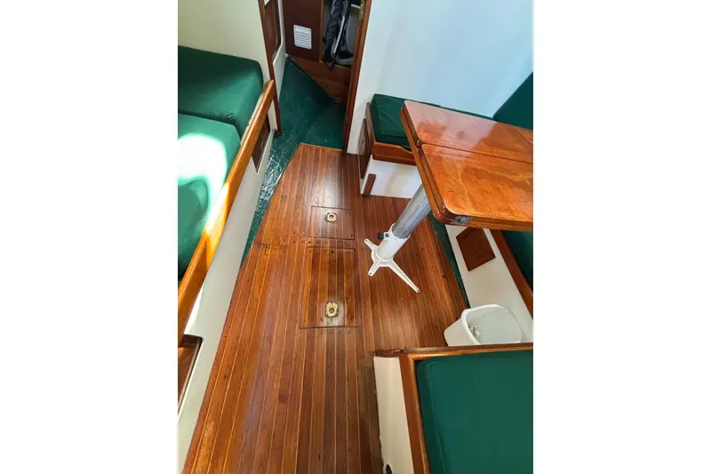 Slide: The Image of Interior of 1968 Spencer 35 sailboat with wooden flooring and green cushioned seating. - 21