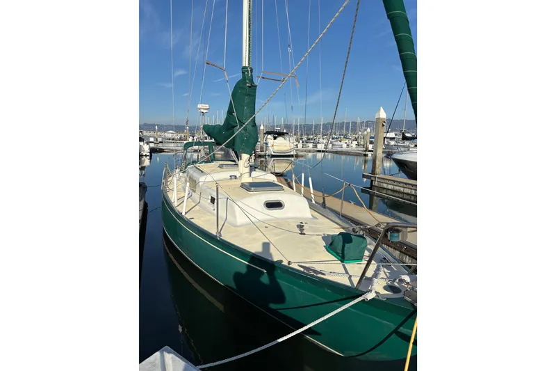 Slide: The Image of 1968 Spencer 35 sailboat docked in a marina, featuring green accents and clear blue skies. - 3
