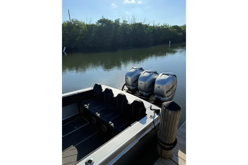 Slide: The Image of 2006 Lazer 40 boat with triple Mercury engines docked by a calm river. - 17