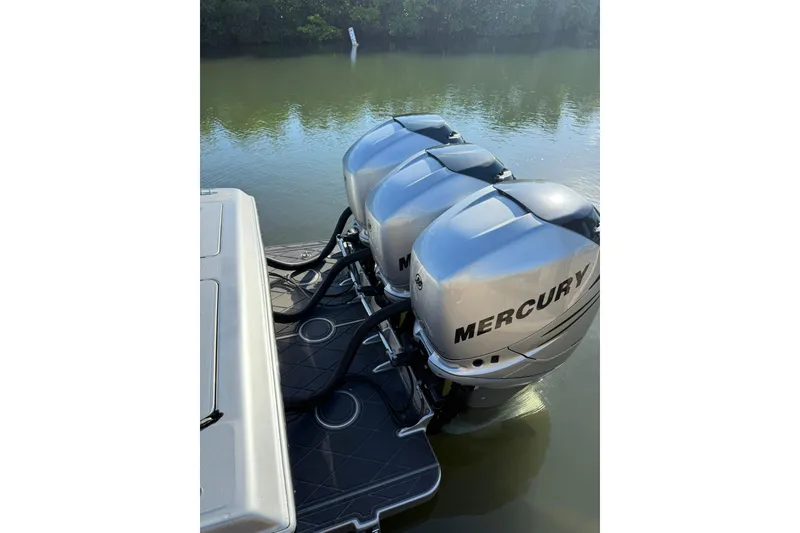 Slide: The Image of Triple Mercury outboard engines on a 2006 Lazer 40 boat, docked on calm water. - 21
