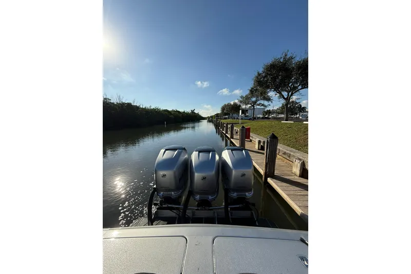 Slide: The Image of Three outboard motors on a 2006 Lazer 40 boat docked by a sunny canal. - 24