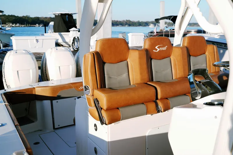 Slide: The Image of 2021 Scout 355 LXF boat with luxurious tan and gray seating at a marina. - 23