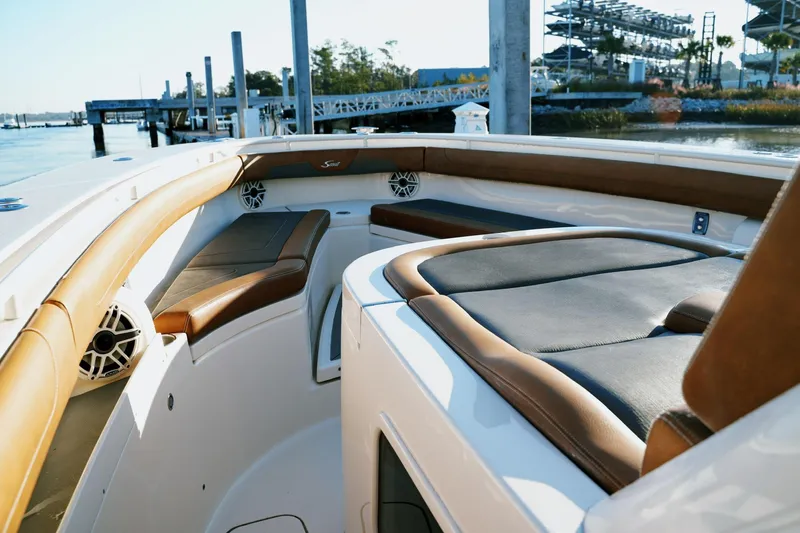 Slide: The Image of 2021 Scout 355 LXF boat interior with luxurious seating and speakers at a marina. - 35