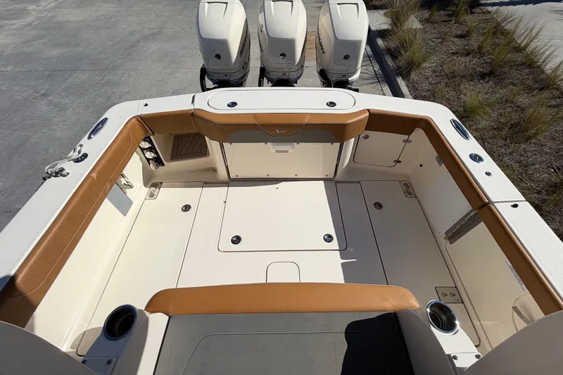 Slide: The Image of 2021 Scout 355 LXF boat deck with triple outboard engines, featuring tan seating and storage compartments. - 45