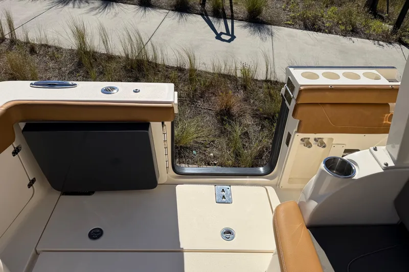 Slide: The Image of 2021 Scout 355 LXF boat interior with seating and cup holders, docked near a grassy area. - 48