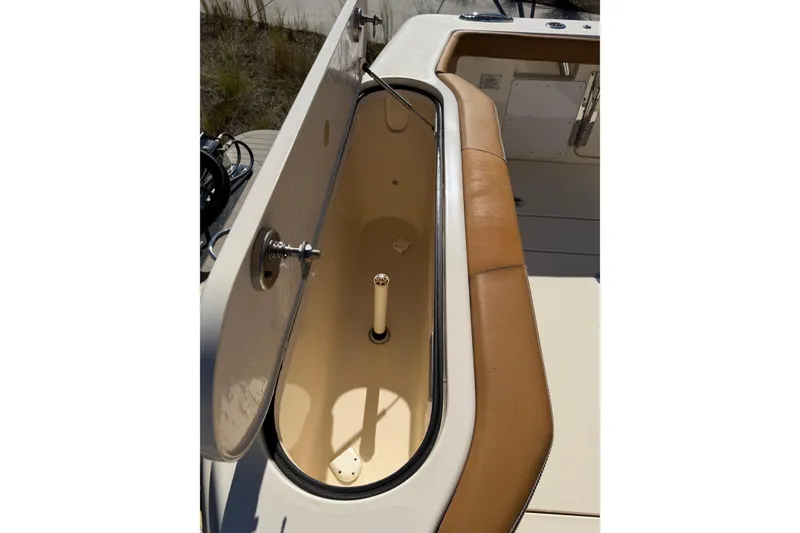 Slide: The Image of 2021 Scout 355 LXF boat storage compartment with open lid and tan seating. - 50