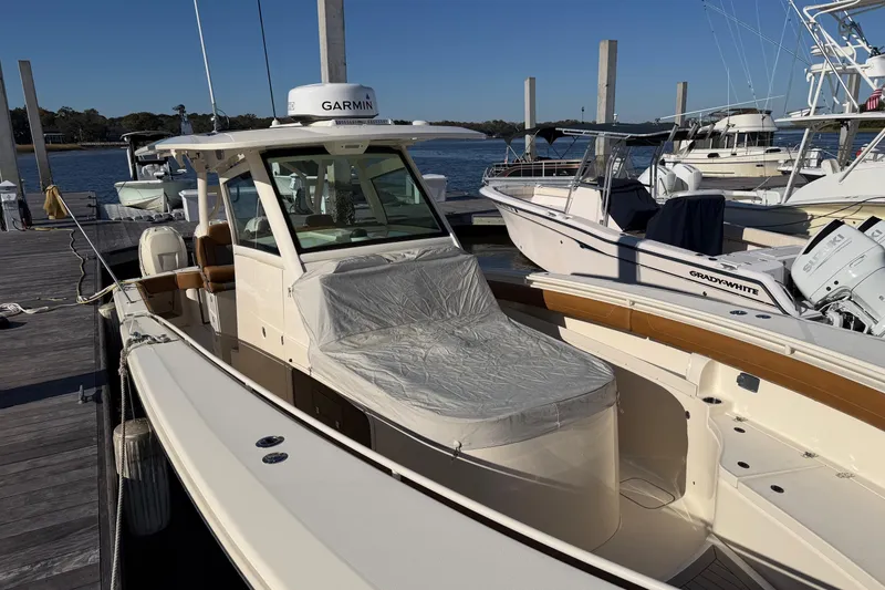 Slide: The Image of 2021 Scout 355 LXF boat docked with protective cover, featuring Garmin equipment. - 56