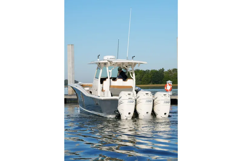 Slide: The Image of 2021 Scout 355 LXF boat with triple 350 engines docked on calm water. - 6