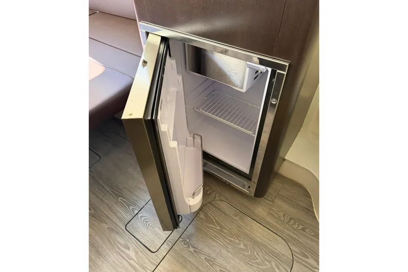 Slide: The Image of Open refrigerator inside 2021 Scout 355 LXF boat, showcasing interior storage space. - 64