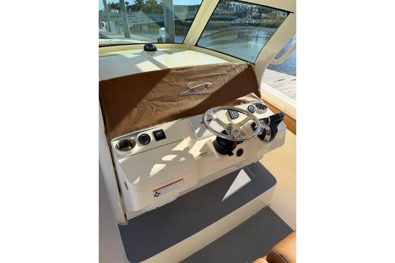 Slide: The Image of 2021 Scout 355 LXF boat helm with steering wheel and controls, dockside view. - 76