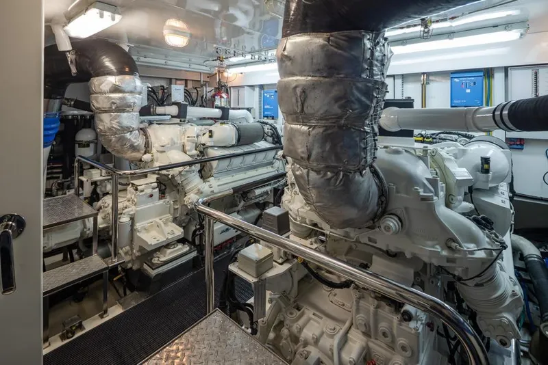 Slide: The Image of Engine room of 2014 Ocean Alexander 85 Cockpit Motoryacht, featuring dual engines and metallic piping. - 63