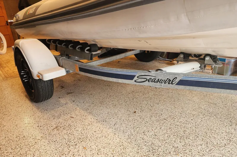 Slide: The Image of Trailer with "Seaswirl" branding holding a boat, parked on a speckled garage floor. - 71