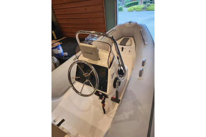 Slide: The Image of Inflatable boat with Garmin navigation, steering wheel, and controls, inside a garage. - 72