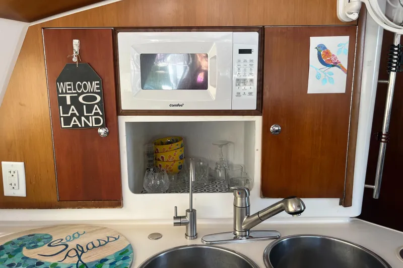 Slide: The Image of Galley of 2000 Fountaine Pajot Belize 43 with microwave, sink, and decorative signs. - 10
